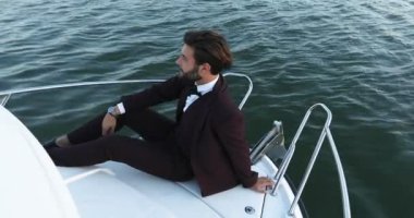 Şık işadamı yat veya tekne karşı bir deniz yüzme burun üzerinde oturuyor. Lüks seyahat ve çalışma.