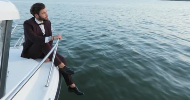 Elegante hombre de negocios en un yate o barco contra un mar. Él está satisfecho con el éxito en su negocio y su equipo de socios, estaban en el negocio de lujo viajando y trabajando . — Vídeo de stock
