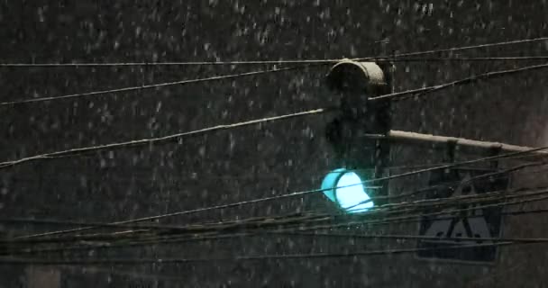 Во время снегопада светит светофор. Плохая погода, дождь и сырой снег на дороге. Отражения ночного света. фары — стоковое видео