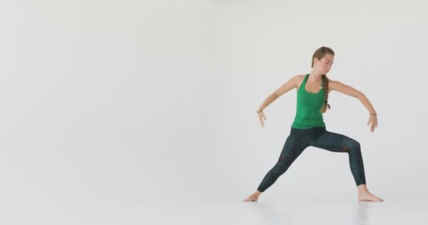 Aantrekkelijke jonge vrouw die zich uitstrekt in het venster. jonge vrouw praktijken yoga bewegingen en posities in een studio — Stockvideo