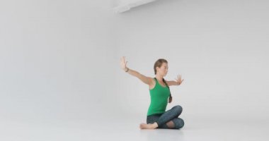 Beyaz arka planda yoga yapan sportif genç bir kadın. Vücut ve zihinsel gelişim arasındaki sağlıklı yaşam ve doğal denge kavramı.