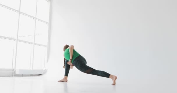 Vrouw een yoga-oefening te doen. Yoga in de lichte studio. Harmonieuze mensen. Vreedzame mensen. Functies van het menselijk lichaam. — Stockvideo