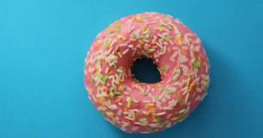 Parlak ve renkli serpilir çörek yakın çekim makro mavi bir arka plan üzerinde iplik vurdu. Lezzetli tatlı çörek bir plaka üzerinde döner. Üstten Görünüm