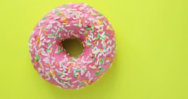 Ljusa och färgglada beströdda donut närbild makro skott spinning på gul bakgrund. Läckra söta donut roterar på en tallrik. Ovanifrån — Stockvideo