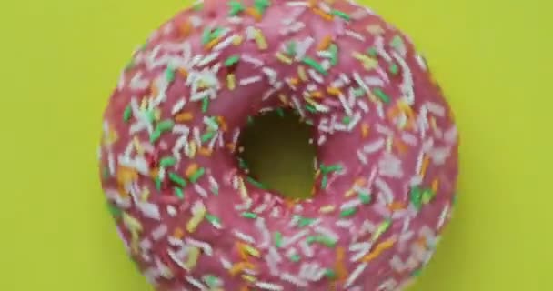 Köstliche süße Donut rotierenden auf einem Teller. Ansicht von oben. hell und bunt bestreut Donut Nahaufnahme Makroaufnahme Drehen auf gelbem Hintergrund. — Stockvideo
