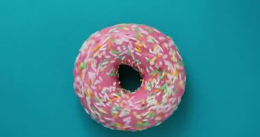 Lezzetli tatlı çörek bir plaka üzerinde döner. Üstten Görünüm. Parlak ve renkli serpilir çörek yakın çekim makro mavi bir arka plan üzerinde iplik vurdu. Lezzetli tatlı çörek bir plaka üzerinde döner. Üstten Görünüm