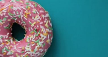 Lezzetli tatlı çörek bir plaka üzerinde döner. Üstten Görünüm. Parlak ve renkli serpilir çörek yakın çekim makro mavi bir arka plan üzerinde iplik vurdu. Lezzetli tatlı çörek bir plaka üzerinde döner. Üstten Görünüm