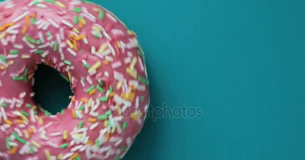 Delicious sweet donut rotating on a plate. Top view. Bright and colorful sprinkled donut close-up macro shot spinning on a blue background. Delicious sweet donut rotating on a plate. Top view — Stock Video