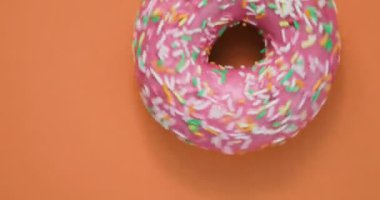 Lezzetli tatlı çörek bir plaka üzerinde döner. Üstten Görünüm. Parlak ve renkli serpilir çörek yakın çekim makro iplik turuncu bir arka plan üzerine vurdu..