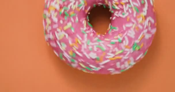 Ljusa och färgglada beströdda donut närbild makro skott snurrar på en orange bakgrund. Läckra söta donut roterar på en tallrik. Ovanifrån — Stockvideo