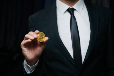 İşadamı altın Bitcoin siyah arka planda tutan bir takım