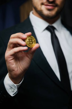 Blockchain kavramı: siyah arka plan üzerine altın Bitcoin tutan işadamı el