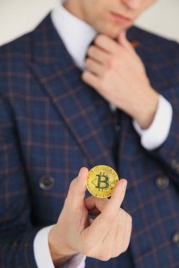 Altın bitcoin - uluslararası sanal cryptocurrency sembolü tutan takım elbiseli adam. Beyaz izole.