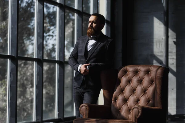 Bonito homem de negócios caucasiano vestido com o terno perto da janela no estúdio interior loft — Fotografia de Stock