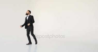 Stüdyoda tek başına çekilen ve beyaz arka planda izole edilmiş bir iş adamı çeşitli komik danslar yapar.