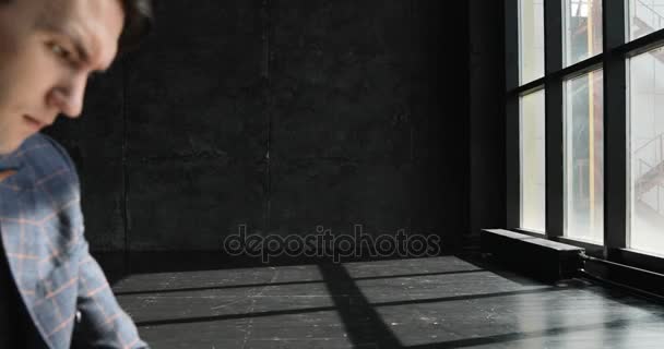 Úspěšný mladý muž pracující v domácí kancelář v loft stylu. Stylový bederní muž v obleku, pracující na pozadí blavk zdi prozářený sluncem — Stock video