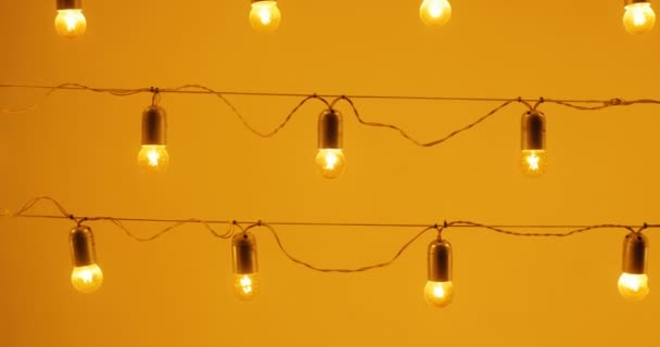 Ampoules sur un fil contre le mur, concept de vacances, ampoules orange, lampe décoration maison la nuit, lanterne en verre — Video