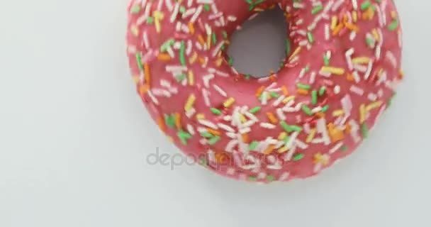 Delicious sweet donut rotating on a plate. Top view. Bright and colorful sprinkled donut close-up macro shot spinning on a white background. — Stock Video