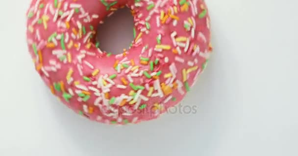 Νόστιμο γλυκό ντόνατ περιστρέφεται σε ένα πιάτο. Στο πάνω μέρος. Φωτεινό και πολύχρωμο ψεκασμένο ντόνατ κοντινό πλάνο μακρο γυρίζοντας σε λευκό φόντο. — Αρχείο Βίντεο
