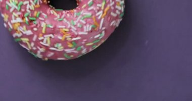 Lezzetli tatlı çörek bir plaka üzerinde döner. Üstten Görünüm. Parlak ve renkli serpilir çörek yakın çekim makro iplik mor bir arka plan üzerine vurdu..