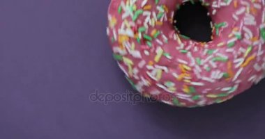 Lezzetli tatlı çörek bir plaka üzerinde döner. Üstten Görünüm. Parlak ve renkli serpilir çörek yakın çekim makro iplik mor bir arka plan üzerine vurdu..