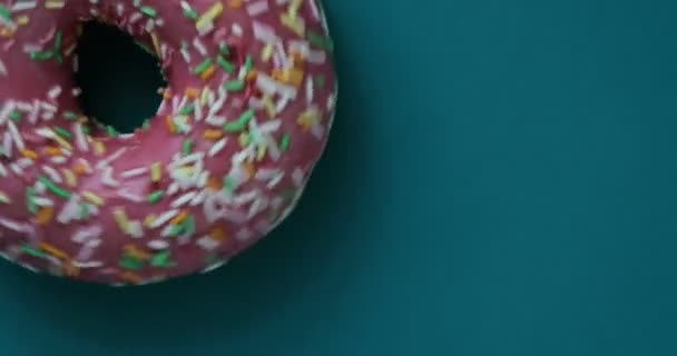 Köstliche süße Donut rotierenden auf einem Teller. Ansicht von oben. helle und bunt bestreute Donut-Nahaufnahme-Makroaufnahme, die sich auf blauem Hintergrund dreht. köstliche süße Donut rotierenden auf einem Teller. Ansicht von oben — Stockvideo
