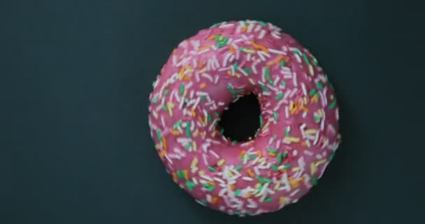 Ljusa och färgglada beströdda donut närbild makro skott snurrar på en svart bakgrund. Läckra söta donut roterar på en tallrik. Ovanifrån — Stockvideo