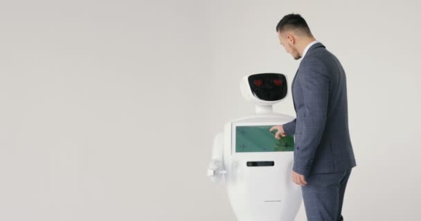 Stylowy mężczyzna komunikuje się z robotem, prasy z tworzywa sztucznego mechaniczne ramię robota, uścisk dłoni. Dziś system cybernetyczny. Nowoczesnych technologii robotów. Autonomicznych robotów humanoidalnych. — Wideo stockowe