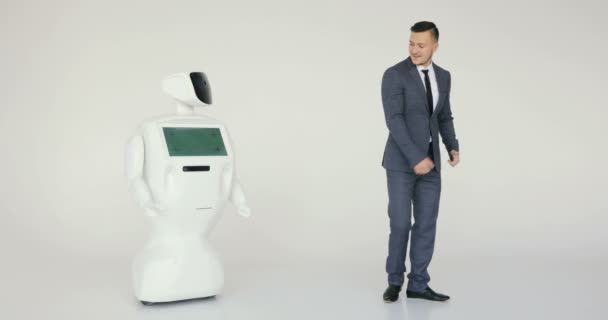 Гуманоидный автономный робот танцует со стильным мужчиной в костюме. Современные роботизированные технологии. Гуманоидный автономный робот — стоковое видео