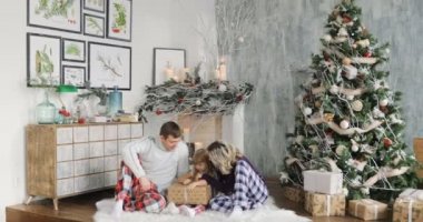 Anne ve kızı Noel ile oynarken sunar oturma odasında. Çocuk için Noel hediyeleri kutularında. Bir çocuk bir Noel hediyesi sahiptir.