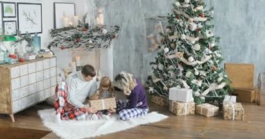 Mutlu aile ile Noel hediyeleri A çocuk katında oturan bir Noel hediyesi sahiptir.