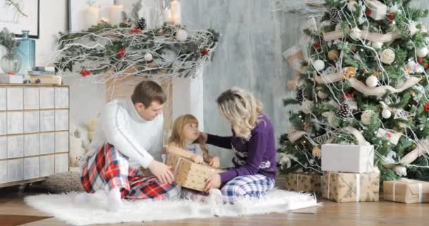 Padres e hija jugando con regalos de Navidad en la sala de estar. Regalos de Navidad en las cajas para el niño. Un niño disfruta de un regalo de Navidad . — Vídeos de Stock