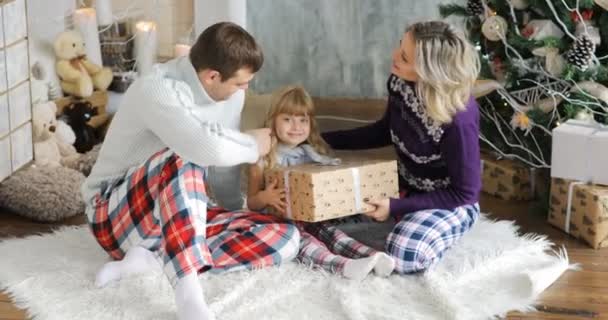Glückliche Familie sitzt am Boden mit Weihnachtsgeschenken ein Kind genießt ein Weihnachtsgeschenk. — Stockvideo
