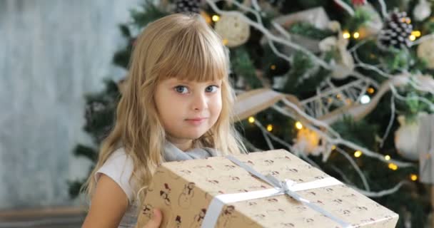 Nettes Mädchen, Vorschulkind, Eröffnungsgeschenke an Weihnachten. kleines Mädchen öffnet am Weihnachtsmorgen ein Geschenk — Stockvideo