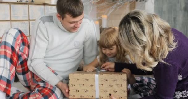 Ouders en dochter spelen met Kerst presenteert in de woonkamer. De giften van het Kerstmis in de vakken voor het kind. Een kind geniet een kerstcadeau. — Stockvideo