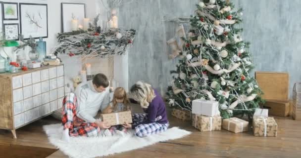 Glückliche Familie sitzt am Boden mit Weihnachtsgeschenken ein Kind genießt ein Weihnachtsgeschenk. — Stockvideo