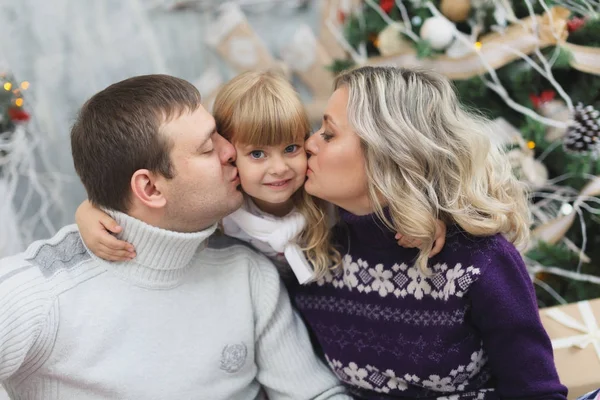 Una familia divertida y feliz con regalos de Navidad. Los padres y el pequeño bebé se divierten cerca del árbol de Navidad en la habitación. Familia cariñosa junto al árbol de Navidad — Foto de Stock