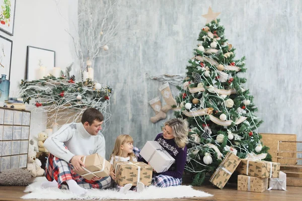 Padres sonrientes dando regalo de Navidad a su hija en casa. Un niño disfruta de un regalo de Navidad . — Foto de Stock