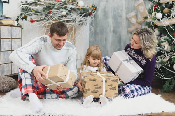 Familia feliz en Navidad regalos de apertura sentado en el suelo en casa — Foto de Stock