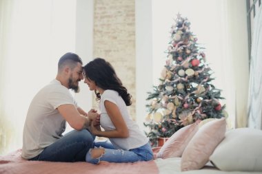 Mutlu çift yatağa oturmuş severler. Noel iç. Aşıklar birlikte