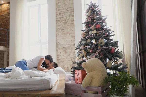 快乐对情侣坐在床上。圣诞节的内部。恋人在一起 — 图库照片