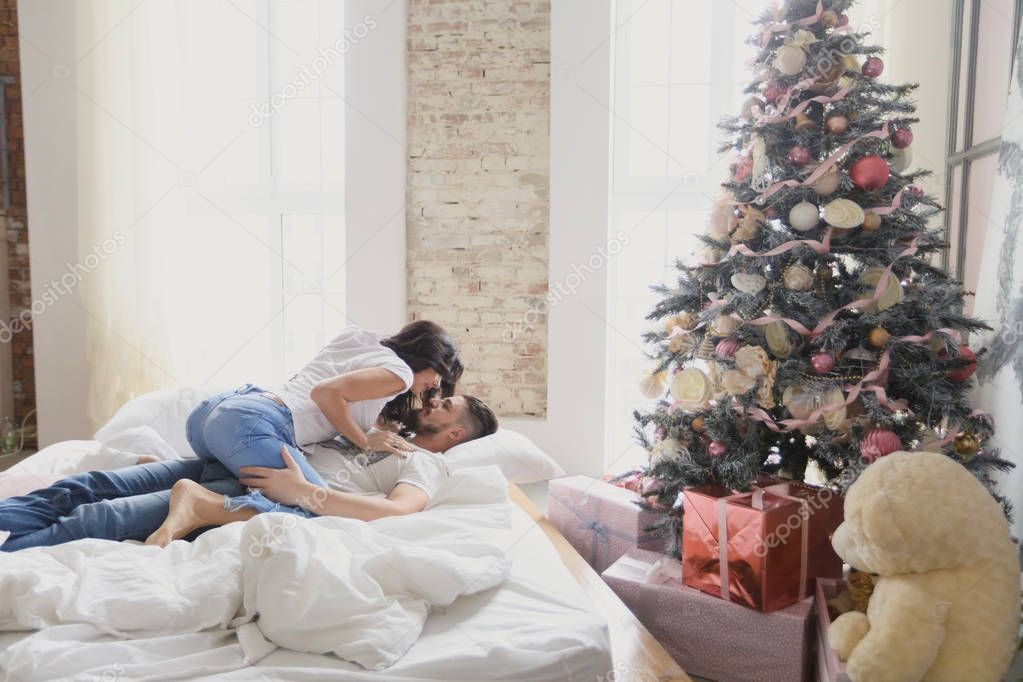 A loving couple celebrates Christmas together. Lovers on a loft bed.