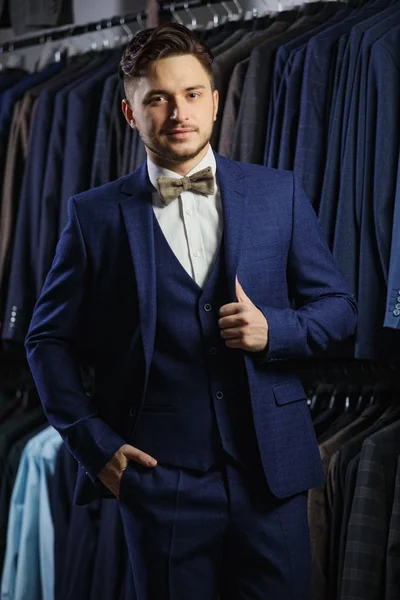 Hombre de negocios caucásico guapo vestido con el traje. En el fondo trajes clásicos y chaquetas — Foto de Stock