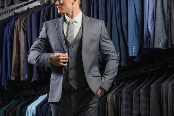 Hombre de negocios caucásico guapo vestido con el traje. En el fondo trajes clásicos y chaquetas — Foto de Stock