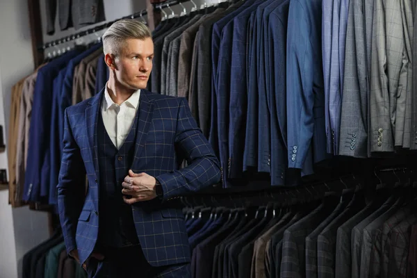 Hombre de negocios caucásico guapo vestido con el traje. En el fondo trajes clásicos y chaquetas — Foto de Stock