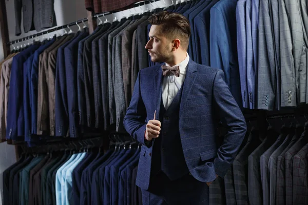 Gutaussehender Geschäftsmann im klassischen Anzug. ein junger, stilvoller Mann in einer Jacke. Es steht im Showroom, probiert Klamotten an, posiert. Werbefoto — Stockfoto