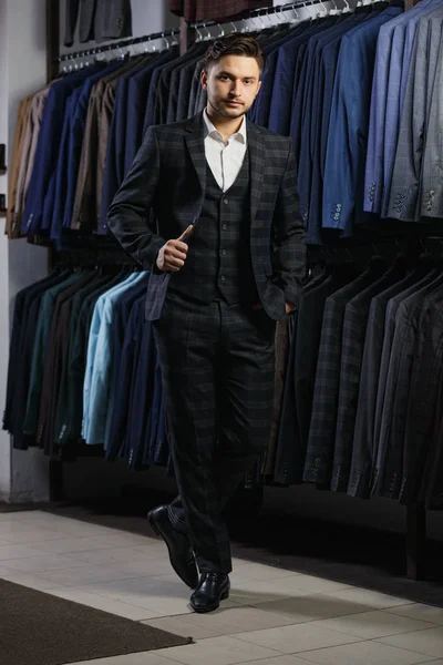 Un bell'uomo d'affari in abito classico. Un giovane uomo elegante con una giacca. E 'nello showroom, a provare vestiti, a posare. Pubblicità foto — Foto Stock