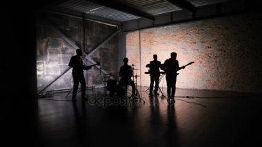 siluet konser rock grubunun şarkıcı sanatçı, gitar, davul, klavyeci ile sahnede performans. Müzik video punk, ağır metal veya rock grubu.