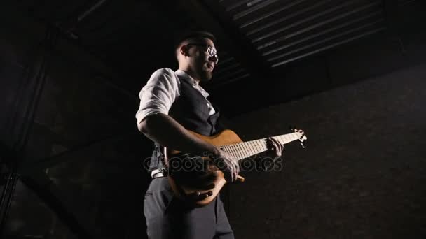 Молодой музыкант играет на гитаре в лофт-студии — стоковое видео