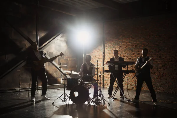 Müzik grubu ve moda. Rock ve şarkı şarkı çalmaya elbiseli yakışıklı genç adamlar. Bantları siluetleri ile bir konser.